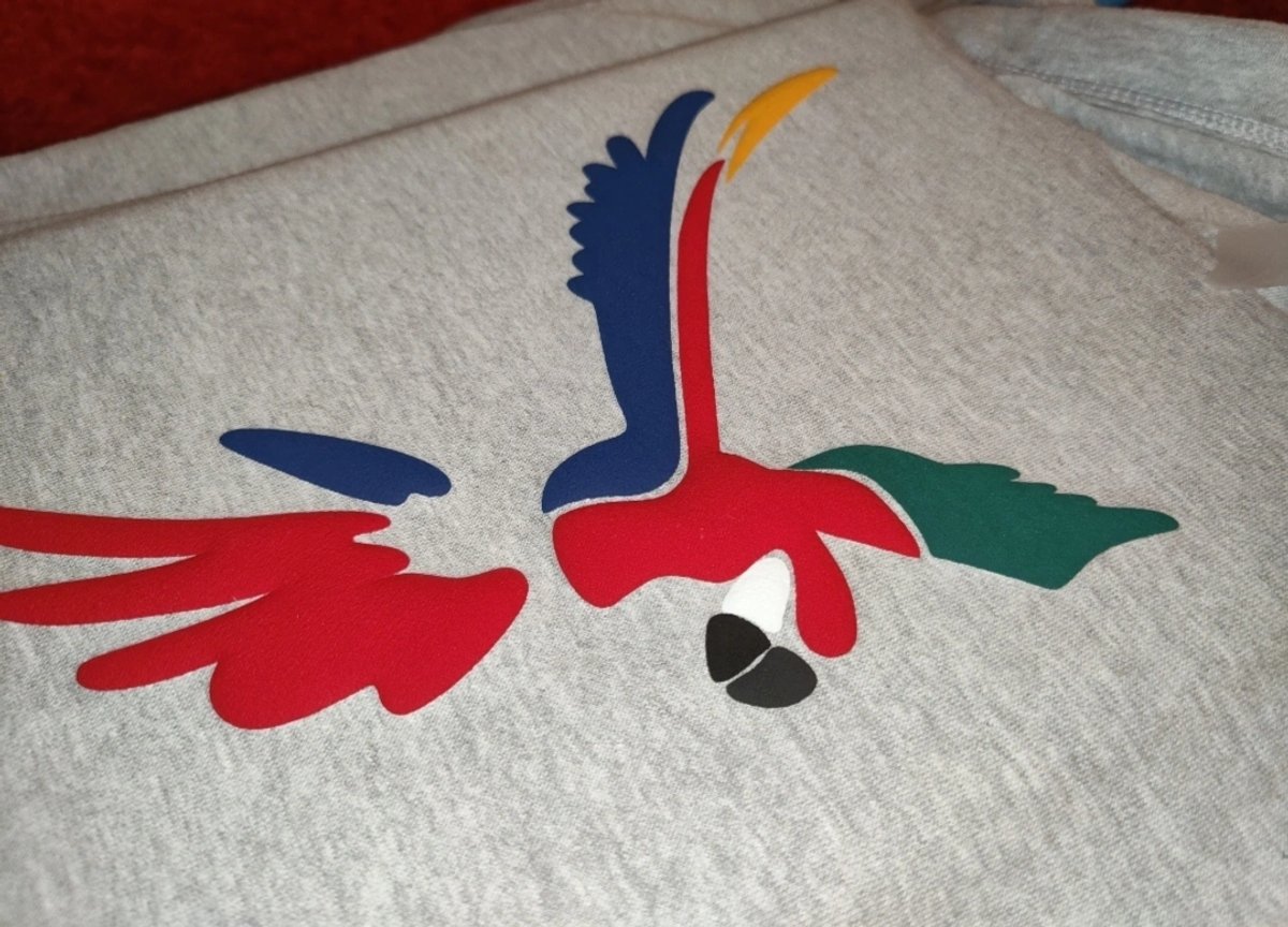 A hand-cut macaw design laid out on a grey T-shirt ready for pressing